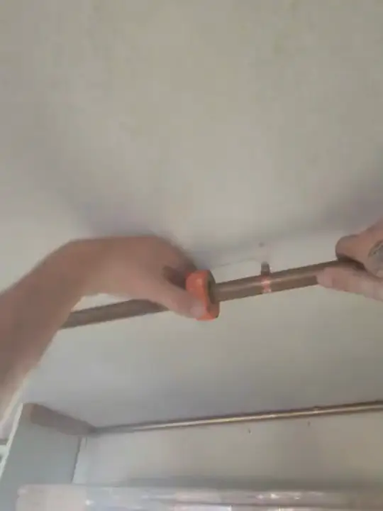 Through Jacob's glasses: a length of copper held up against a ceiling